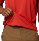 A man lifts the hem of his Columbia Mens Zero Rules™ Light Technical T-Shirt, revealing a patterned inner lining with cooling technology, paired with tan pants.