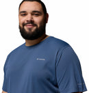A man with a short beard and dark hair smiles wearing a blue Columbia Mens Zero Rules™ Light Technical T-Shirt, known for its moisture-wicking fabric, standing against a plain white background.