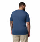 A man with tattoos stands facing away, wearing a Columbia Mens Zero Rules™ Light Technical T-Shirt in blue and khaki pants, set against a plain white background.
