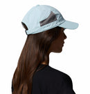 A woman with long brown hair, wearing a black t-shirt and the Columbia Tech Shade II Cap, faces away to reveal the back and side of this lightweight hiking hat against a white background.