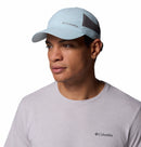 A man in a light blue Columbia Tech Shade II Cap and pale grey t-shirt looks slightly left against a white background. The cap is lightweight with mesh sides for breathability.