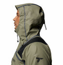 A man in profile wears the Columbia Mens Whistler Peak Waterproof Shell Jacket in olive green with black trim and adjustable drawstrings, set against a plain white background.