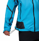 A person adjusts the hem drawstring of a Columbia Mens Whistler Peak Waterproof Shell Jacket in bright blue. The image highlights the lower section, black zippers, and their hand adjusting the jacket.