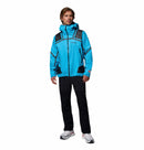 A man faces forward wearing the Columbia Mens Whistler Peak Waterproof Shell Jacket in bright blue with black accents, paired with black pants and white sneakers against a plain white background.