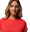 A woman with wavy blonde hair wears the Columbia Womens Zero Rules Light Technical T-shirt, designed for hiking with sweat-activated cooling, as she stands against a white background and looks at the camera with a neutral expression.