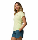 A woman with long blonde hair wears the Columbia Womens Zero Rules Light Technical T-shirt, which features sweat-activated cooling, and teal running shorts, standing against a plain white background.