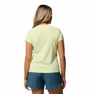 A woman with blonde hair, seen from behind, wears the Columbia Womens Zero Rules Light Technical T-shirt and teal shorts with sweat-activated cooling. Set against a plain white background—ideal for hiking adventures.