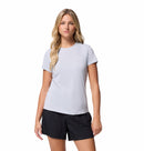 A woman with long blonde hair wears the Columbia Womens Zero Rules Light Technical T-shirt with sweat-activated cooling and black shorts, standing against a plain white background.