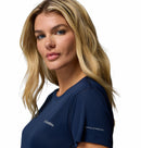 A woman with long blonde hair wears a Columbia Womens Zero Rules Light Technical T-shirt, featuring sweat-activated cooling, and looks at the camera against a white background.