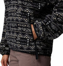 Wearing a Columbia Womens Sequoia Grove™ Printed Half Zip Fleece, made from recycled polyester, with a black and white pattern, right hand in the zippered pocket, paired with light brown pants; only torso and upper legs are visible.