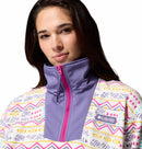 A woman wears the Columbia Womens Sequoia Grove™ Printed Half Zip Fleece, featuring a vibrant pattern with a high purple collar and pink zipper, posing against a white background.