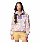 A woman with long, dark hair and a relaxed expression wears the Columbia Womens Sequoia Grove™ Printed Half Zip Fleece and tan shorts against a white background. The fleece is made from recycled polyester and features a colorful print.