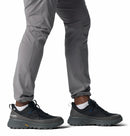 A person in gray pants walks in Columbia Mens Tellurix Titanium Outdry Hiking Shoes, black waterproof footwear with rugged Vibram Megagrip soles, shown from the knees down.