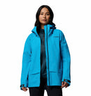 A woman with long dark hair wears the Columbia Womens Saudan Pro™ 3L Shell Jacket in bright blue over a dark zip-up top, standing against a plain white background.