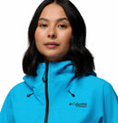 A woman with medium-length dark hair smiles slightly as she faces forward, modeling the Columbia Women’s Saudan Pro™ 3L Shell Jacket against a plain white background.