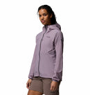 A person stands against a plain white background wearing brown shorts and the Columbia Womens Khyex Pro™ Wind Jacket—a light purple, ultralight, wind-resistant jacket with UPF 50 and a front zipper featuring the Columbia logo on the chest.