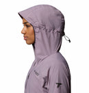 A woman wears the Columbia Womens Khyex Pro™ Wind Jacket in light purple, shown in profile with the hood up and drawstring secured. The ultralight, wind-resistant jacket is set against a white background.