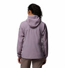 A person with curly hair, seen from behind, wears a light purple Columbia Womens Khyex Pro™ Wind Jacket with UPF 50 protection and beige shorts against a plain white background.