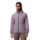 A woman stands facing forward against a white background, wearing the Columbia Womens Khyex Pro™ Wind Jacket in light purple with UPF 50 sun protection and ultralight, wind-resistant design, paired with beige pants.