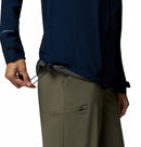 A person in olive green pants adjusts the elastic drawstring at the waist of their Columbia Womens Trailborne 2.5L Waterproof Shell Jacket.