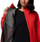 A woman models the Columbia Womens Trailborne 2.5L Waterproof Shell Jacket in bright red, holding it open to reveal the patterned gray lining and highlight its Omni-Tech waterproof features against a plain background.