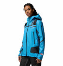 A woman stands confidently against a white background, wearing the Columbia Womens Whistler Peak Waterproof Shell Jacket in bright blue with black accents and a hood.