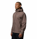 A man wears the Columbia Mens Trailborne 2.5L Waterproof Shell Jacket in taupe, standing against a plain white background, facing slightly to the side with his hands relaxed at his sides.