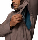 A man in a Columbia Mens Trailborne 2.5L Waterproof Shell Jacket unzips the underarm vent, revealing a blue lining. His face is partially visible, focused on opening the ventilation.