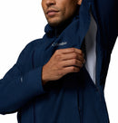 A person wears the Columbia Mens Trailborne 2.5L Waterproof Shell Jacket in navy blue, unzipping an underarm vent to reveal a white mesh lining inside. Only their lower face and upper torso are shown.