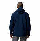 A person stands with their back to the camera, wearing Columbias Mens Trailborne 2.5L Waterproof Shell Jacket in dark blue and gray pants, set against a plain white background.