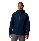 A person stands facing forward against a white background wearing Columbia’s Mens Trailborne 2.5L Waterproof Shell Jacket in navy blue with a hood and light gray pants.