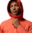 A man confidently zips up a Columbia Mens Trailborne 2.5L Waterproof Shell Jacket in orange, looking at the camera against a plain white background.