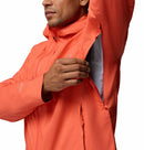 A man in the Columbia Mens Trailborne 2.5L Waterproof Shell Jacket opens a zippered underarm vent, revealing its breathable Omni-Tech lining and showcasing the hiking shells impressive ventilation feature.