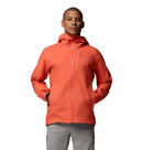 A person wears a bright orange Columbia Mens Trailborne 2.5L Waterproof Shell Jacket with front zipper and pockets, paired with light gray pants, standing facing forward against a plain white background.