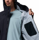 A man wearing a light blue shirt and a Columbia Mens Saudan Pro 3L Waterproof Shell Jacket in black holds open the jacket to reveal its zippered inner pocket and light-colored lining.