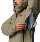 A person in a tan Columbia Mens Saudan Pro 3L Waterproof Shell Jacket with the hood up unzips a large underarm ventilation zipper, showing the inner lining of this waterproof shell.