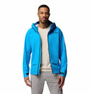 A man faces forward, wearing the Columbia Mens Saudan Pro 3L Waterproof Shell Jacket in bright blue over a light beige shirt and light gray pants. The jacket features a zipper and Columbia logo on the chest. The background is plain white.