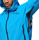 A man in a bright blue Columbia Mens Saudan Pro 3L Waterproof Shell Jacket unzips an underarm vent, showcasing the jacket’s extreme-conditions features with part of his face visible.