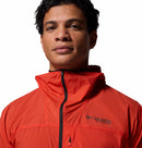A man in a vibrant orange Columbia Mens Khyex Pro™ Wind Jacket with a zippered front stands confidently facing the camera against a white background.