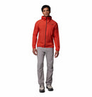 A person stands facing forward against a plain white background, wearing the Columbia Mens Khyex Pro™ Wind Jacket in bright red, featuring water and stain resistance, along with light gray pants and gray hiking shoes.