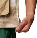 Close-up of a hand holding a piece of fabric with a label, on a white background