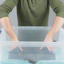 Person wearing a green shirt standing behind a clear plastic container washing dark wetsuit.