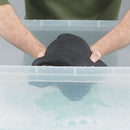 Person holding a black wetsuit above a clear container with water and bubbles.
