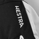 Close-up of a black and white ski glove with “Hestra” embroidered in white on the black portion, highlighting the distinctive design of the Hestra Army Leather Heli Ski Glove.