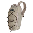 The North Face Borealis Sling Bag in light beige is a compact sling bag made from recycled nylon, featuring a single shoulder strap, front elastic bungee cords, and a top zippered main compartment. The North Face logo appears on the front.