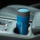 A blue Lifeventure One-Touch Thermal Mug rests in a car cup holder beside the vehicle’s control buttons and a black leather armrest with green stitching.