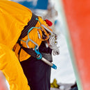 Person wearing a yellow jacket with climbing gear on a blurred background