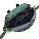 A green Terra 3-Litre Bum Bag by The North Face, made from recycled nylon, sits with its top zipper open to reveal a mesh pocket, a black smartphone, and a gray interior. The bag features yellow zipper pulls and an adjustable strap—ideal for carrying your hiking essentials.