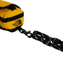 Close-up of The North Face Base Camp Mini Duffel in yellow, featuring a black logo, black straps, and a black-and-white braided cord attached with a black clip.