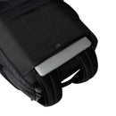 A silver laptop partially tucked into a Great Outdoors Base Camp Boot Bag, with the bag’s top flap unbuttoned and two padded shoulder straps visible on a white background.